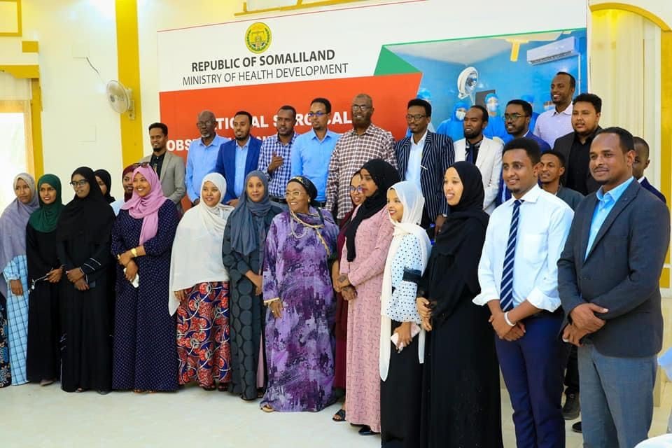 Group of people standing in front of a sign for the Ministry of Health Development in Somaliland.