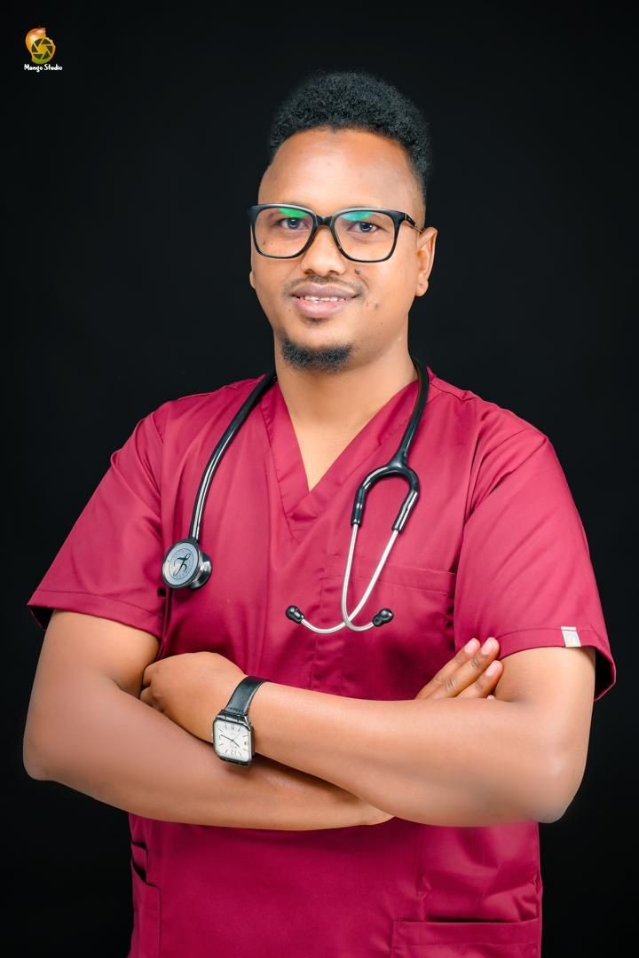 Healthcare professional in red scrubs with stethoscope, smiling with arms crossed.